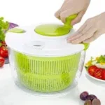 يد تستخدم مقبض مجفف خضار الدوار لتجفيف الورقيات.