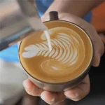 كوب كابتشينو مثالي برغوة غنية تم تحضيرها بواسطة ابريق صنع رغوة الحليب ستانلس ستيل