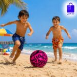 اطفال يركضون ويمرحون بلعب كورة اطفال وردية على رمال الشاطئ