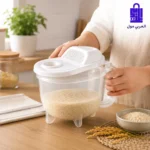 شخص يمسك طبق غسيل الأرز شفاف اللون وممتلئ بالأرز فوق طاولة المطبخ