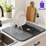 مفرش تجفيف وتصفية الأطباق رمادي ماص للماء موضوع بجانب حوض المطبخ