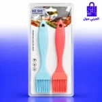 فرشاة سيليكون حمراء يُدهن بها الدجاج المشوي في صينية مع الخضروات وبجانبها فرشاة سيليكون زرقاء