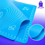 حصيرة فرد العجين السيليكون الأزرق على رخام المطبخ مع نشابة وعجين بيضاوي ومكونات الخبز